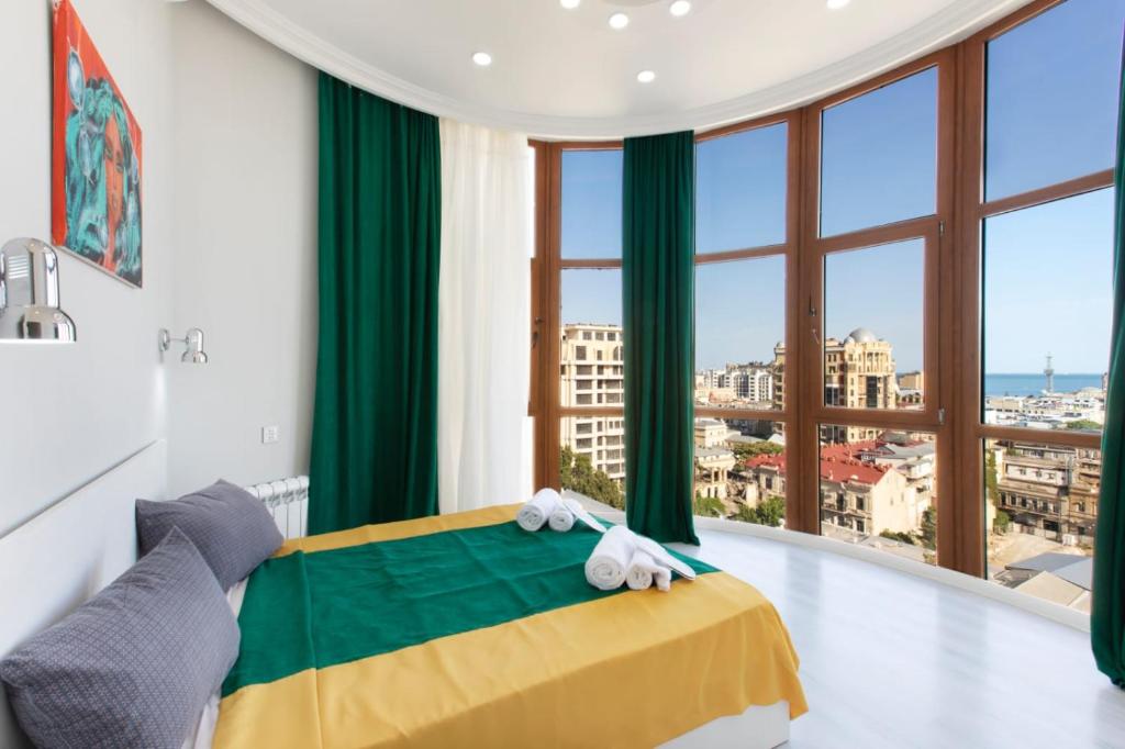 a bedroom with a yellow and green bed with a large window at Leyla Apartments 2 in Baku