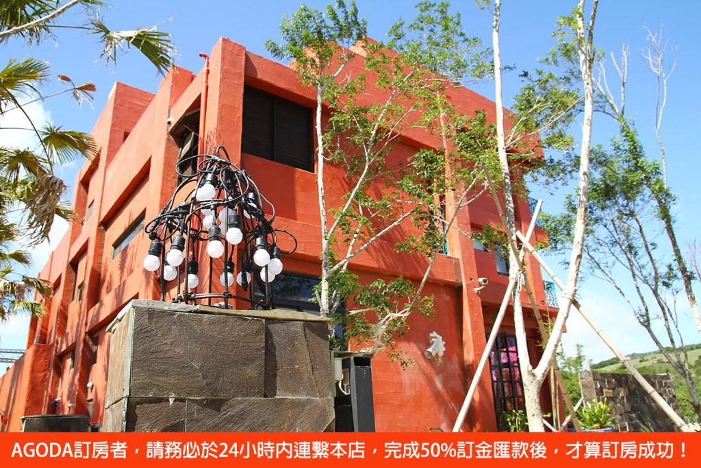 a red building with a statue in front of it at Spring BnB in Kenting
