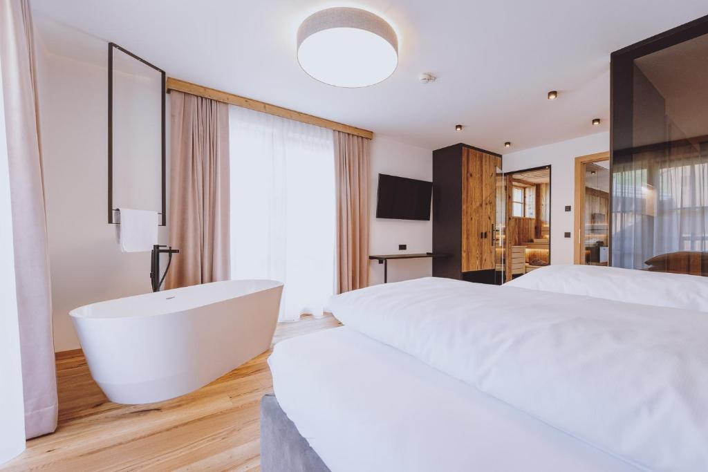 a bedroom with a large white bed and a bath tub at Bergdorf Hotel Zaglgut in Kaprun