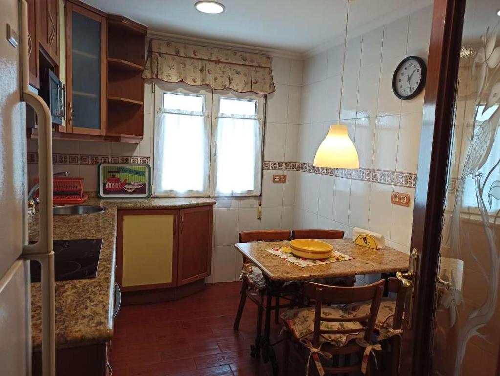 a kitchen with a table and a clock on the wall at Les Playes, Cimavilla in Gijón