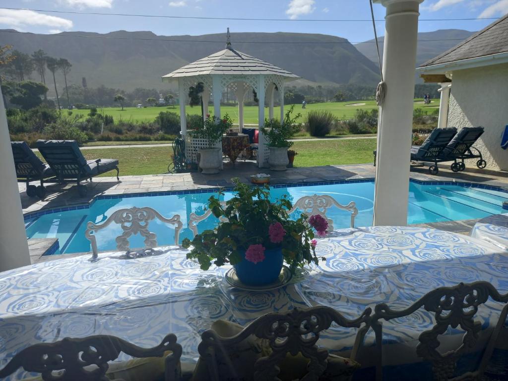 Mulligans Guest Lodge في هيرمانوس: مسبح مع طاولة و شرفة
