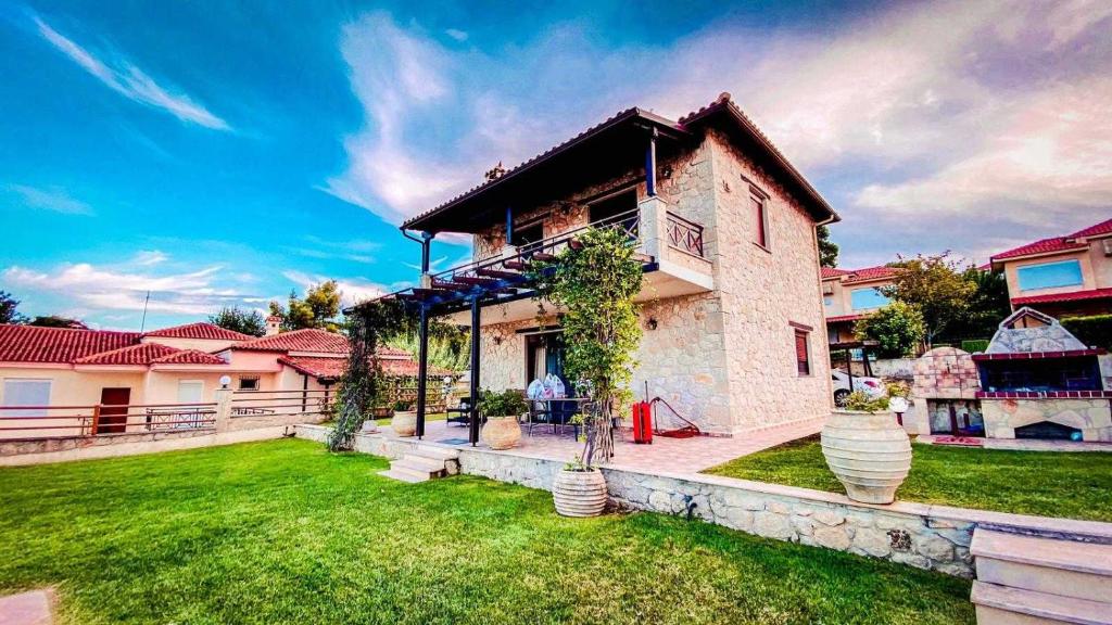 a house with a green lawn in front of it at Jenny Villas in Kriopigi