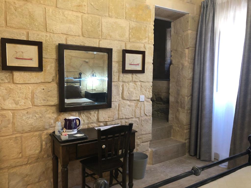 una parete in pietra con specchio e tavolo in legno di The Hidden Gem Boutique Hotel a Rabat