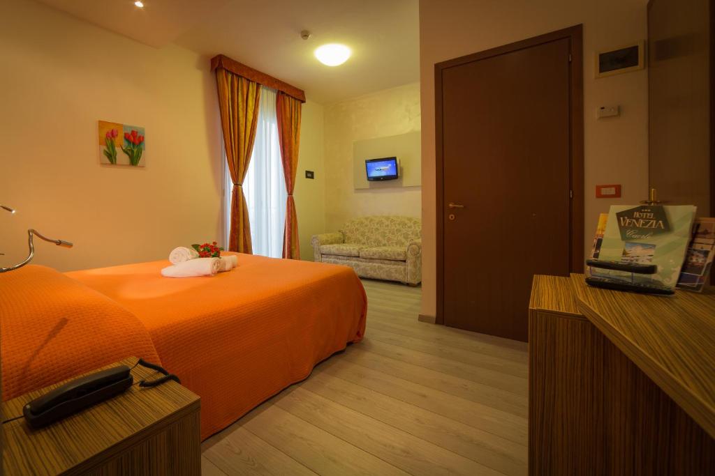a bedroom with an orange bed and a living room at Hotel Venezia in Caorle