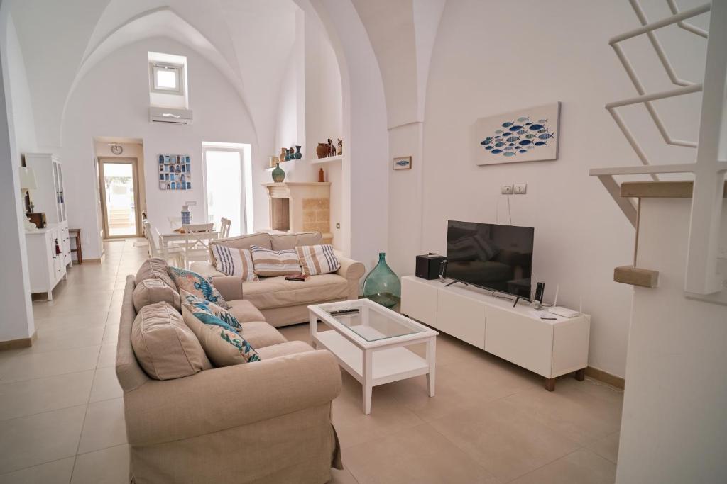 a living room with two couches and a tv at Casa Margherita - typical salento house in Castrignano del Capo