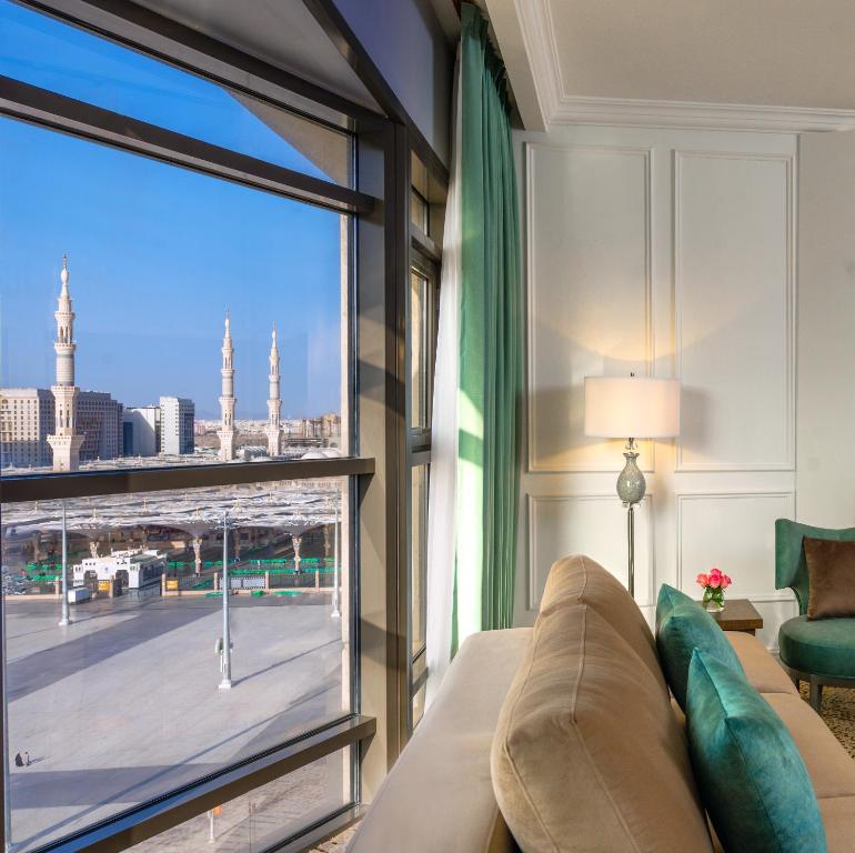 a living room with a couch and a large window at Mias Al Madina Hotel in Al Madinah