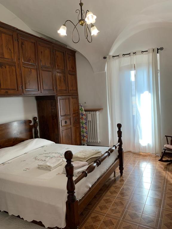 sypialnia z łóżkiem z drewnianymi szafkami i żyrandolem w obiekcie Coccinella San Marco w mieście Pacentro
