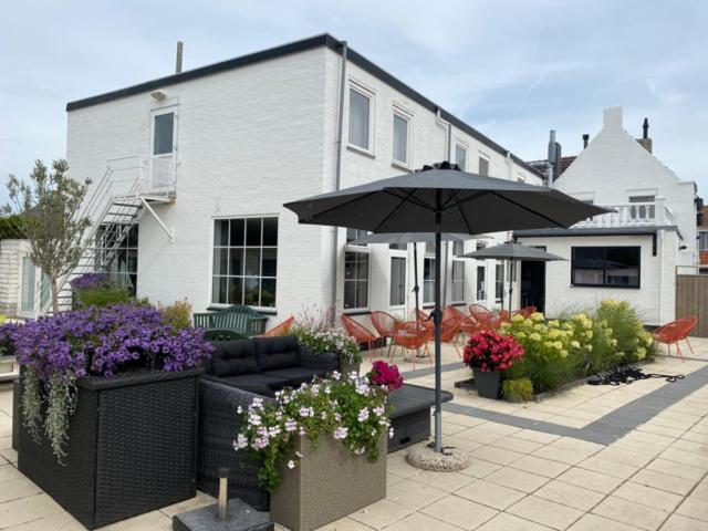 a patio with an umbrella and flowers in front of a house at Hotel Maurice in Nieuwvliet