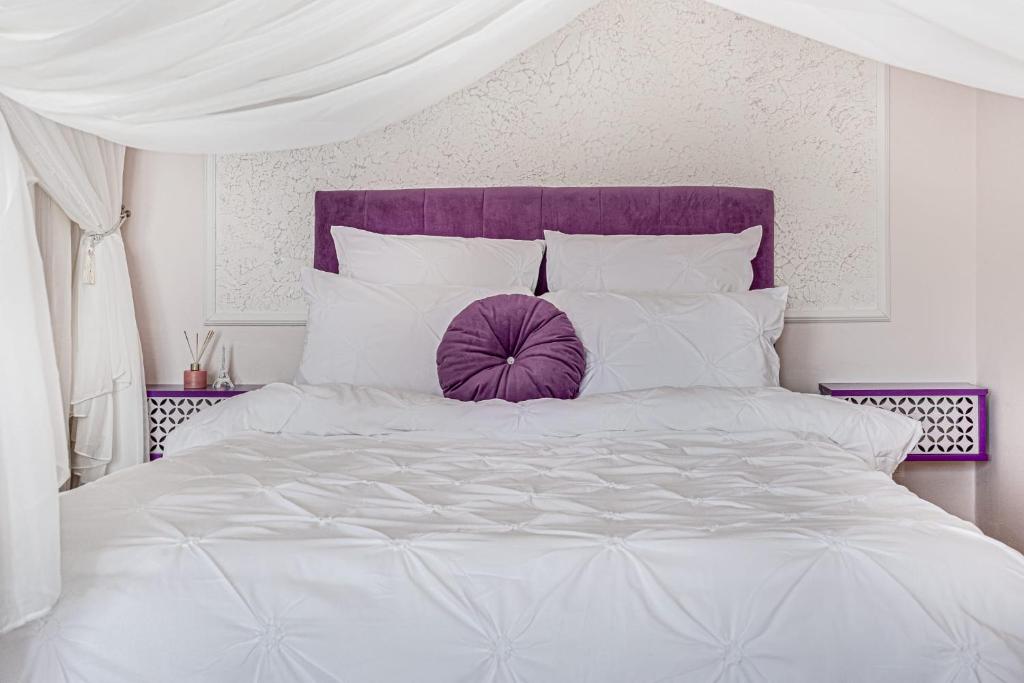 a white bed with a purple headboard and white pillows at ARI Purple Studio in Arad
