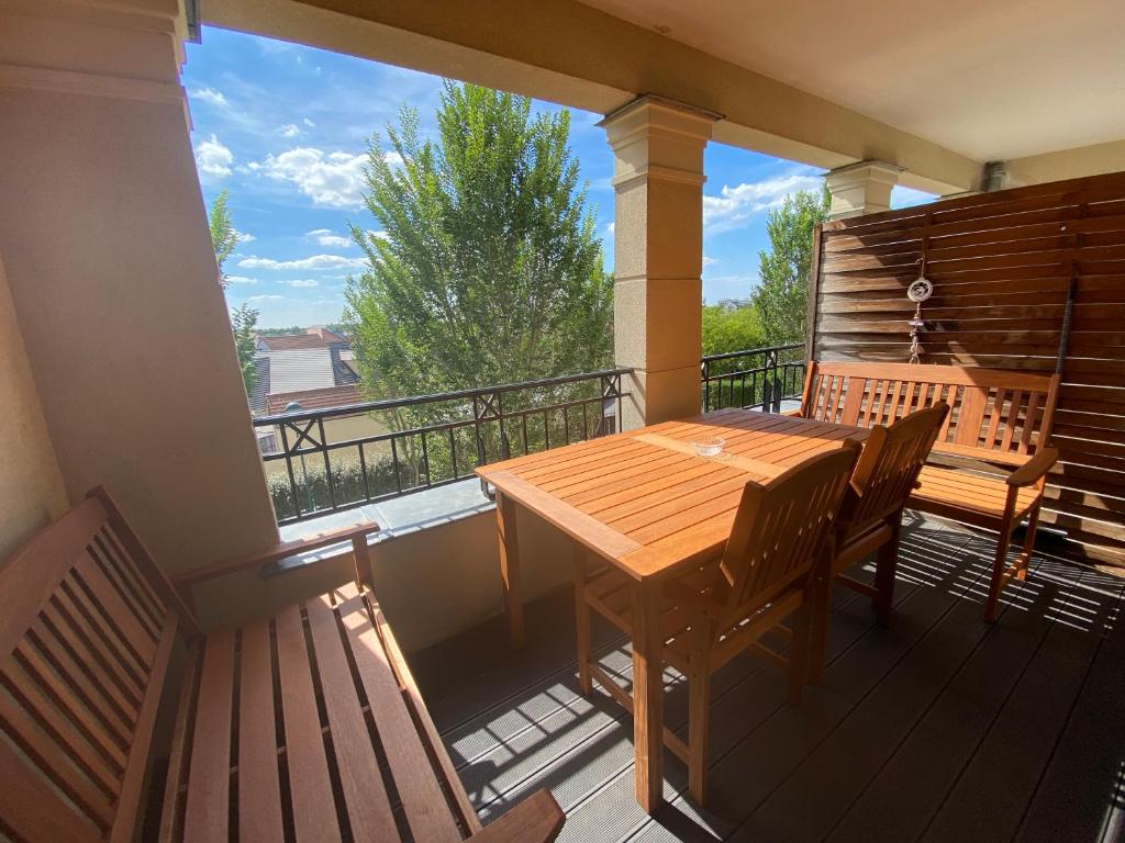 een veranda met een houten tafel en banken op een balkon bij T5 Disney Paris/Val d’Europe in Serris