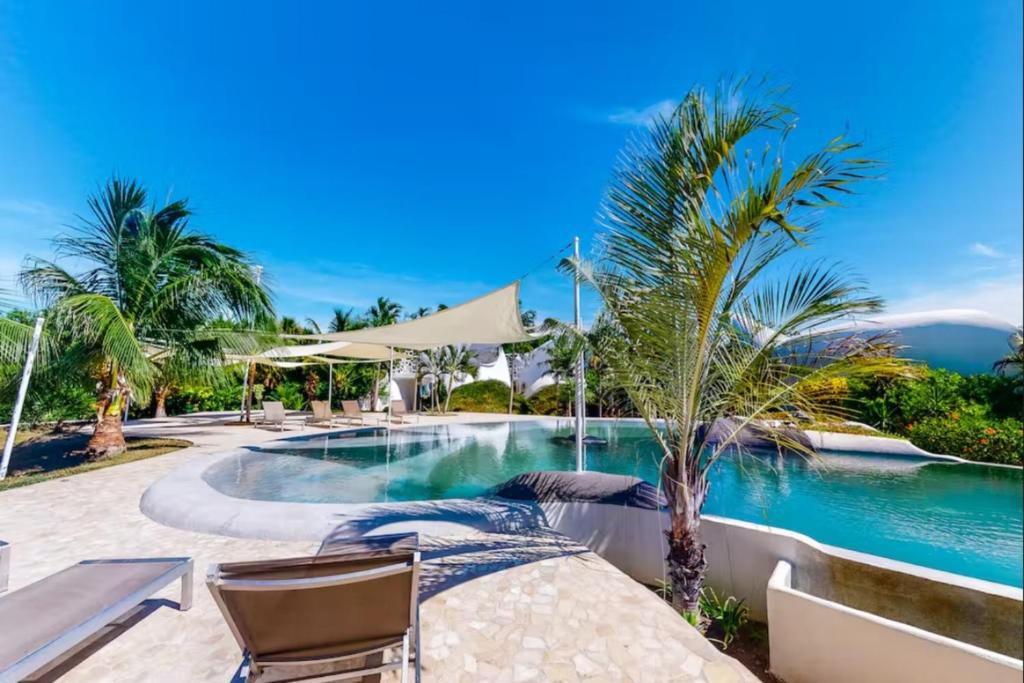 una piscina en un complejo con sillas y palmeras en Alterhome Swan villas with swimming pool and ocean views, en Placencia Village