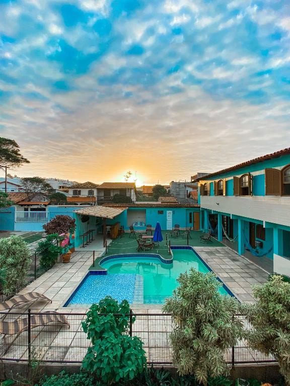a view of the pool at a resort with a sunset at Pousada Brisa da Praia in Arraial do Cabo