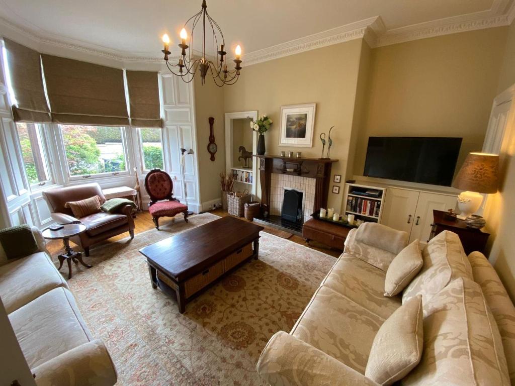 een woonkamer met een bank en een open haard bij Braid Rd Stunning Villa in Edinburgh