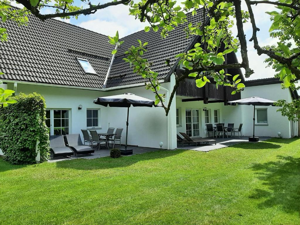 ein weißes Haus mit Stühlen und Sonnenschirmen im Hof in der Unterkunft Ferienwohnung Stricker 1/1 in Walkenried