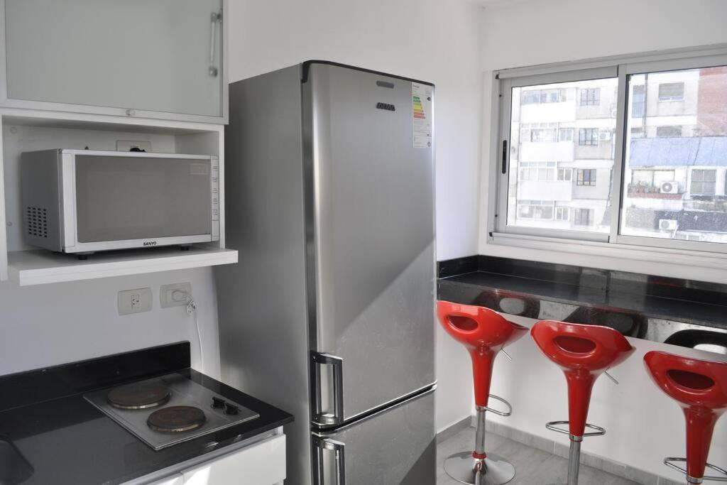 cocina con taburetes rojos frente a una refrigerador en Departamento en Recoleta - Con pileta, parilla, gym - Piso 2 en Buenos Aires