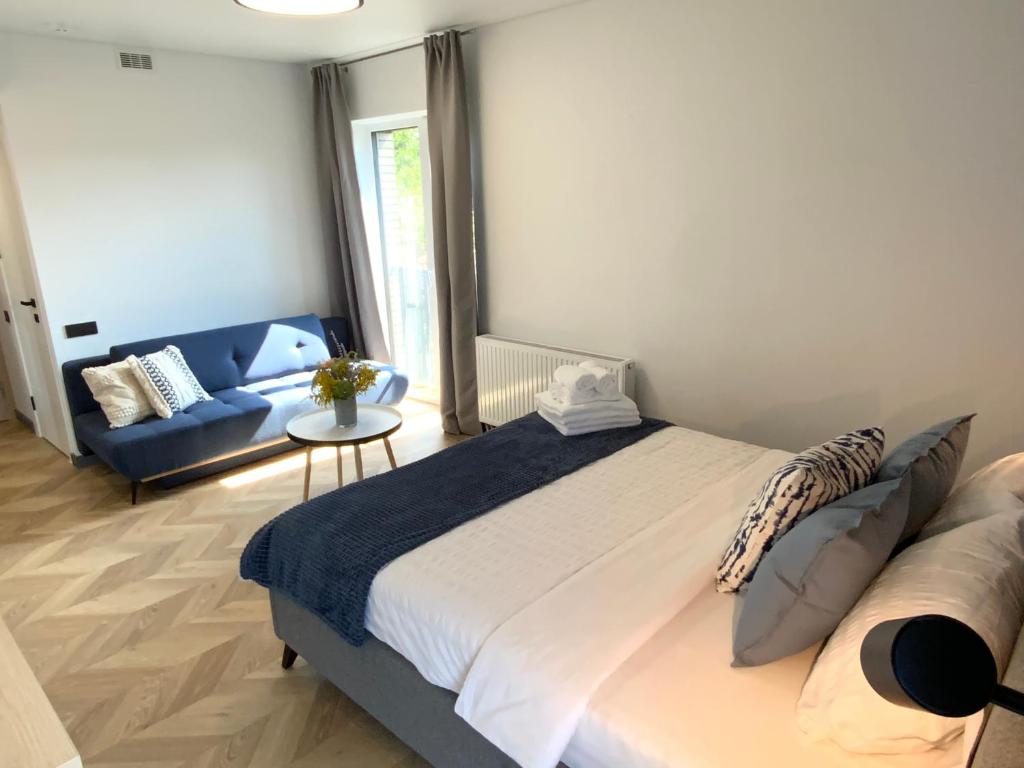 a bedroom with a large bed and a blue couch at Salt Garden Apartments in Druskininkai
