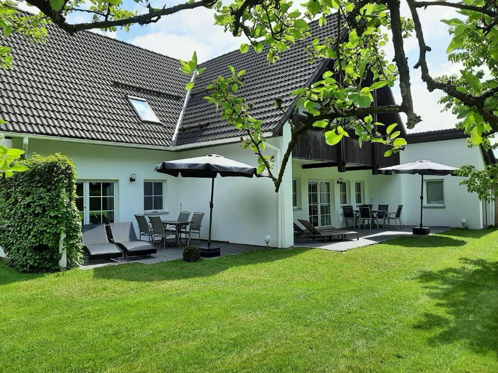 una casa blanca con sillas y sombrillas en el patio en Ferienwohnung-Stricker-2-1-Typ-B-Terrasse, en Walkenried