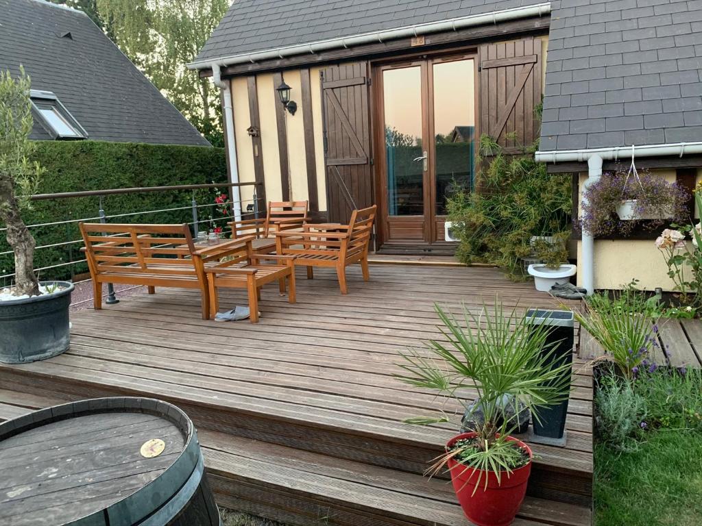 a wooden deck with benches and a table at Le chalet Normand in Merville-Franceville-Plage