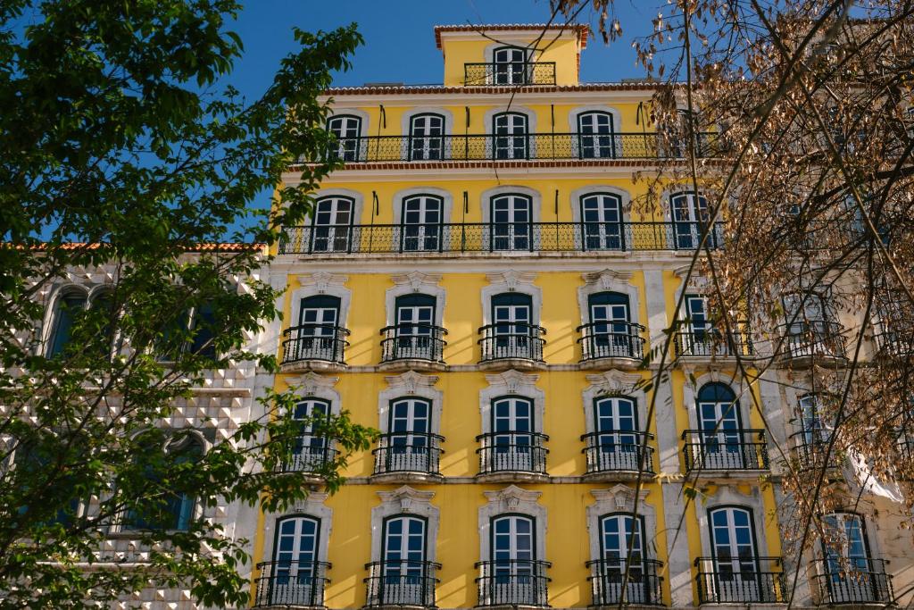 Varandas de Lisboa - Tejo River Apartments & Rooms في لشبونة: مبنى اصفر ويوجد بلكونات بجانبه