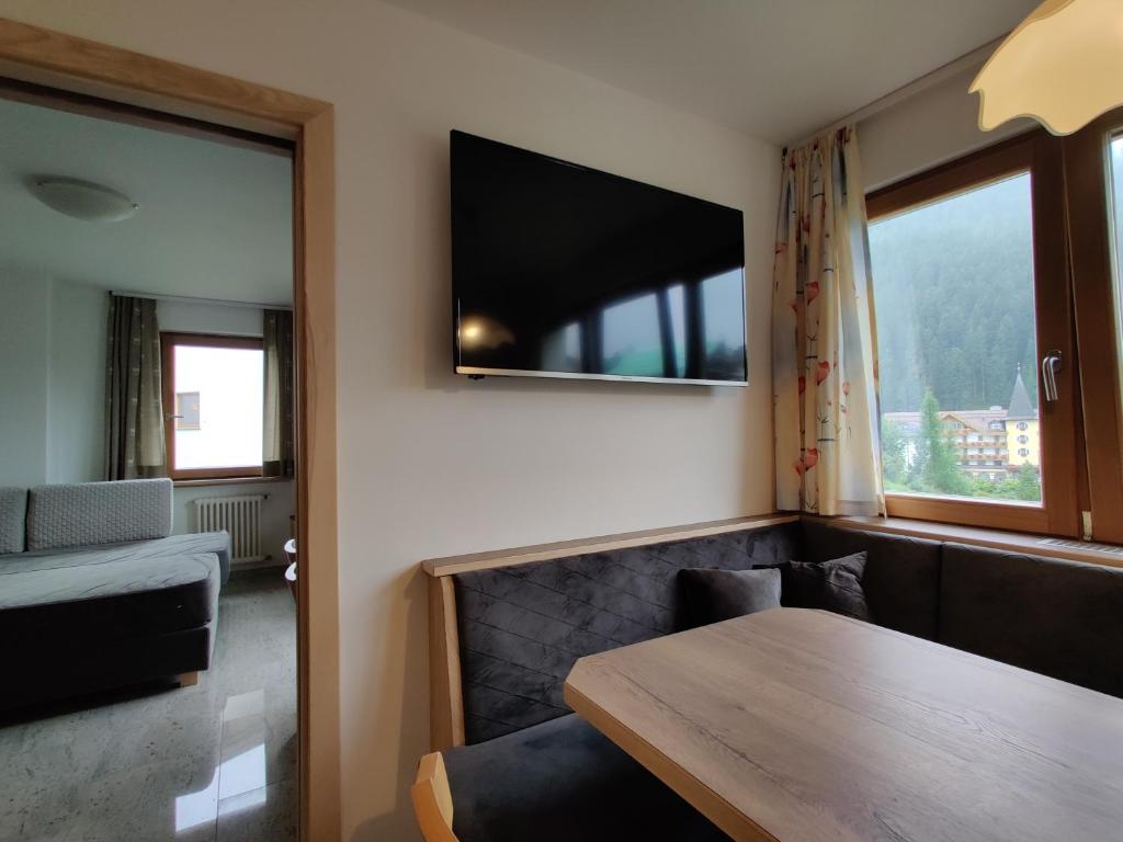 Pokój ze stołem i telewizorem na ścianie w obiekcie Eguia w mieście Selva di Val Gardena