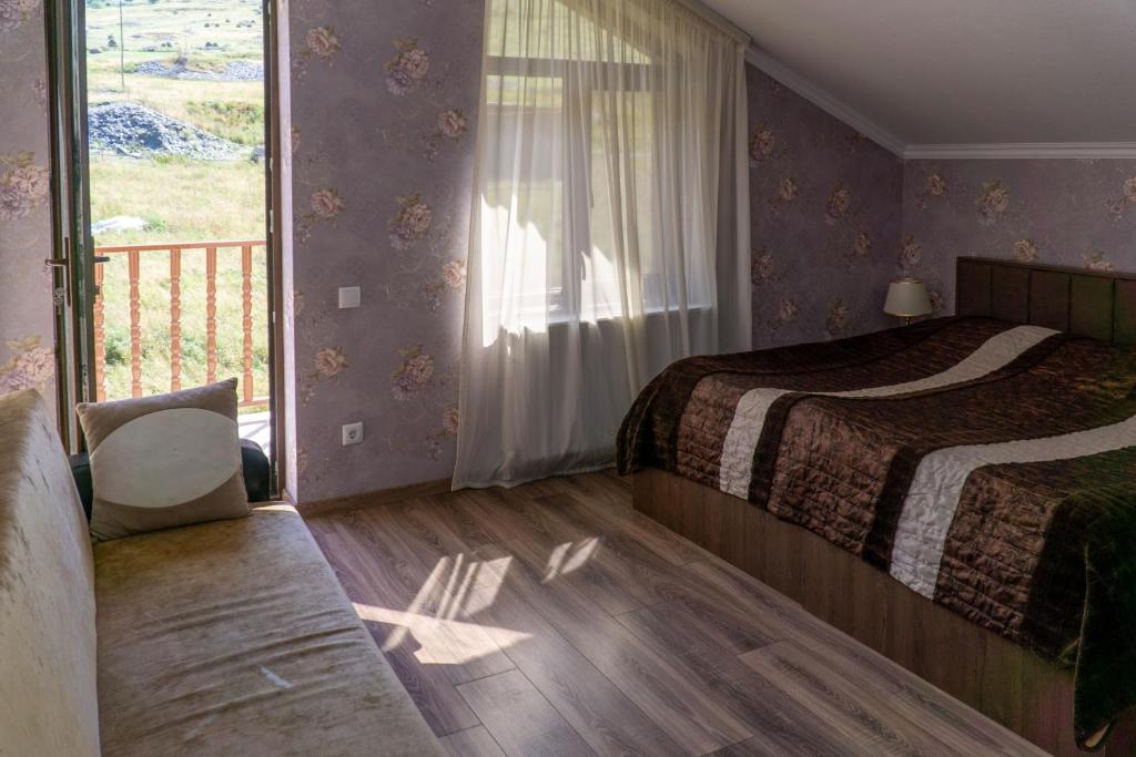 a bedroom with a bed and a balcony at Hotel Diamond Kazbegi in Stepantsminda
