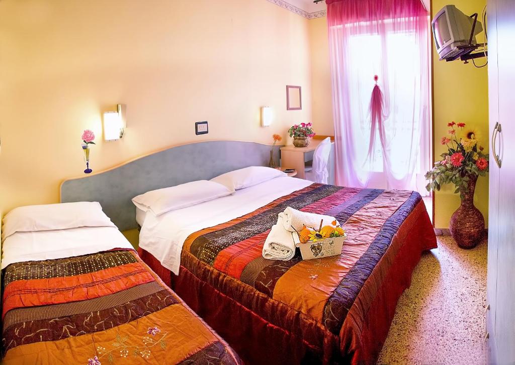 リミニにあるHotel Vittorio Veneto Riminiのベッド2台と窓が備わるホテルルームです。