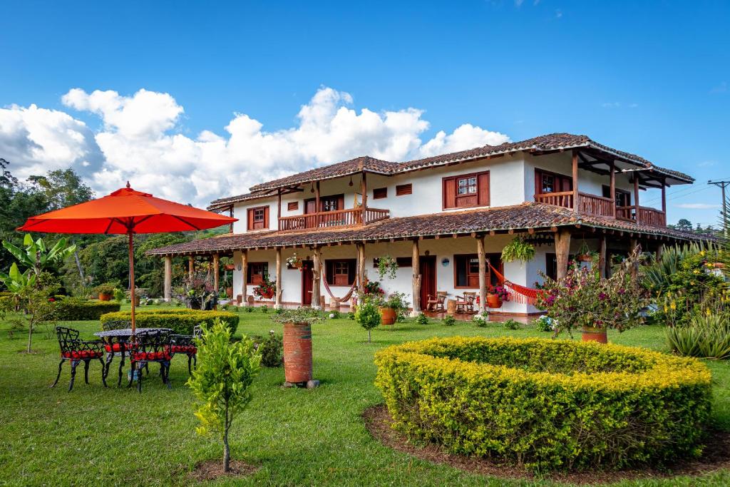 ein Haus mit einem Tisch und einem Sonnenschirm im Hof in der Unterkunft Hotel Estorake San Agustin Huila in San Agustín
