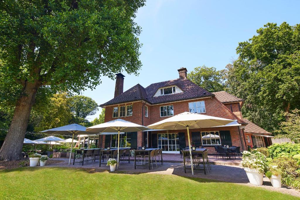 a house with tables and umbrellas in front of it at Auberge Du Bonheur in Tilburg