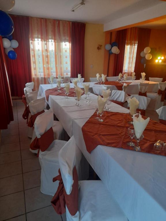 a room with white tables and chairs with wine glasses at Alexandra&Alex in Horezu