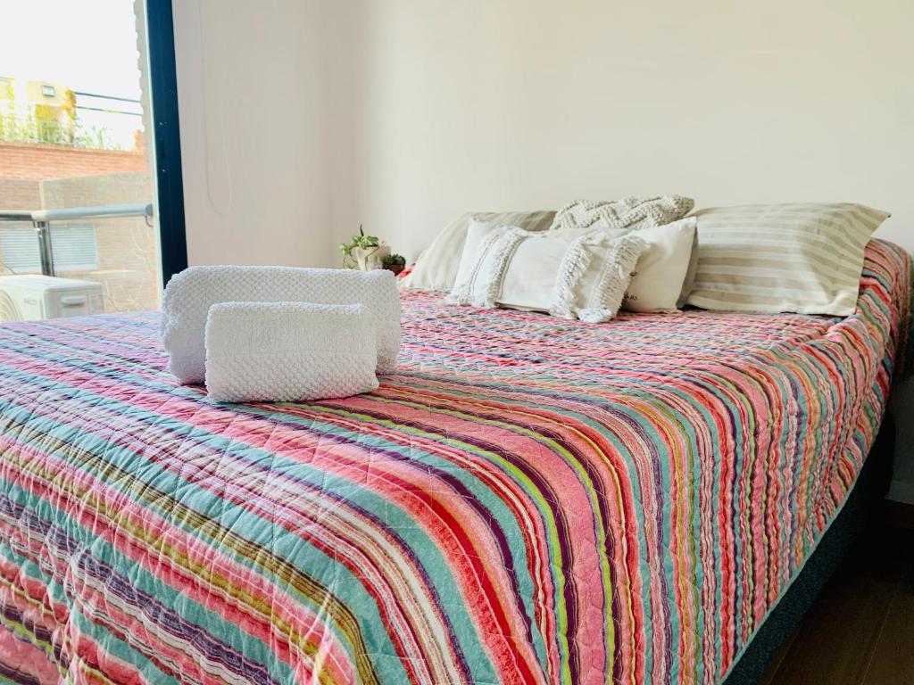 łóżko z kolorowym kocem i poduszkami w obiekcie Depto Genova, Zona Norte, Cochera disponible w mieście Rosario