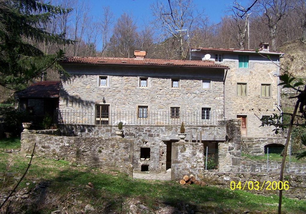 una vieja casa de piedra en medio de un campo en Il Molino, en Bagni di Lucca