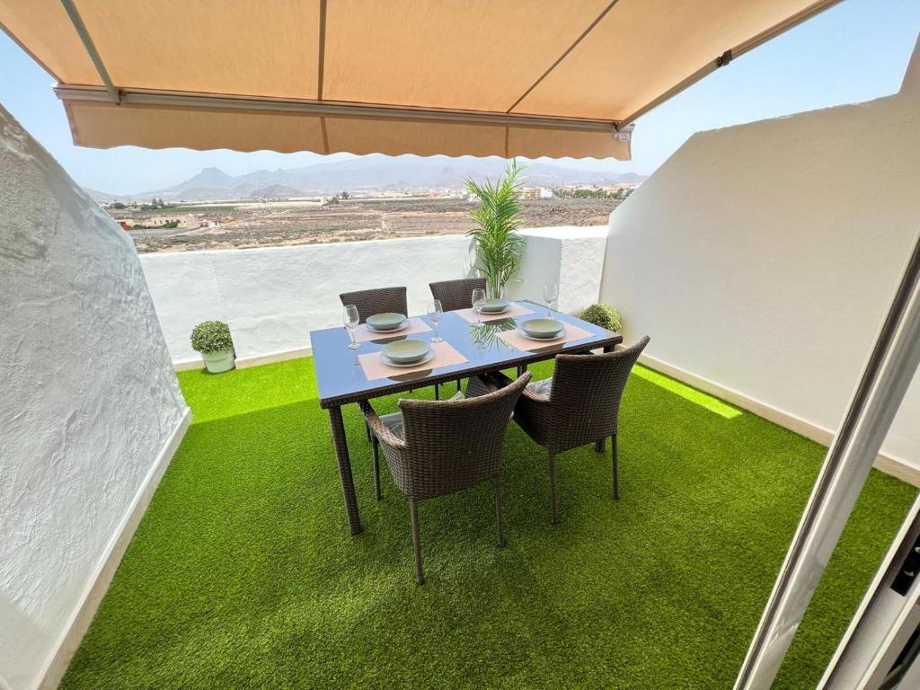 een tafel en stoelen op een patio met gras bij ÁTICO VISTA TEIDE in Arona