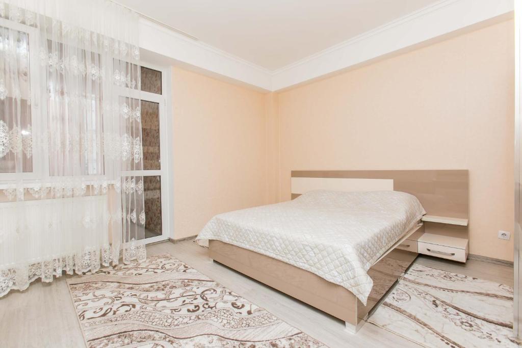 a white bedroom with a bed and a window at Apartament spatios in complex residential in Chişinău