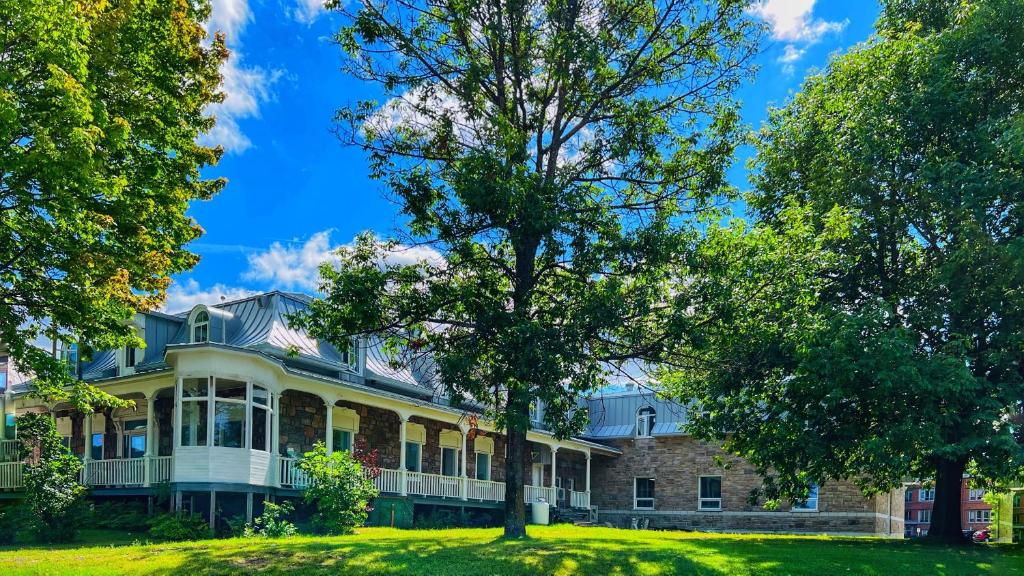 una casa grande con un árbol delante en Auberge Le St-Alexis, en La Baie