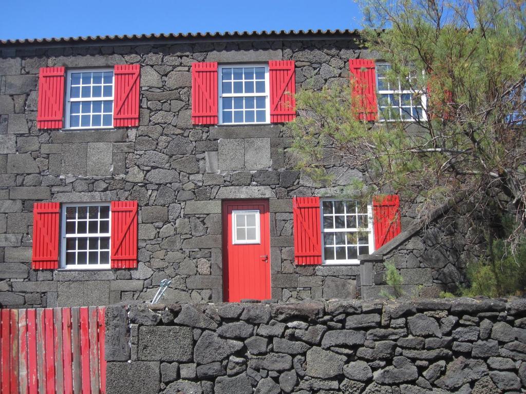 un edificio de piedra con ventanas rojas y puerta roja en Casa do Jardim de Lava en Arcos