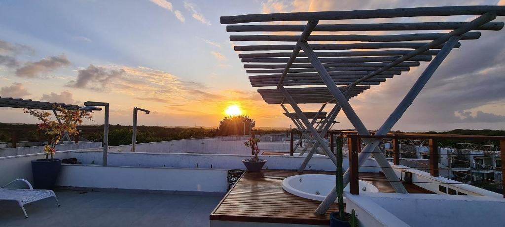 d'un balcon avec une baignoire sur le toit et le coucher du soleil. dans l'établissement Brisas do Amor Apto 109, à Pipa