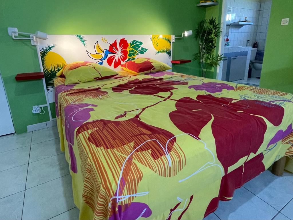 una camera da letto con un letto con un piumone colorato di Colibri de la Pointe a Le Robert