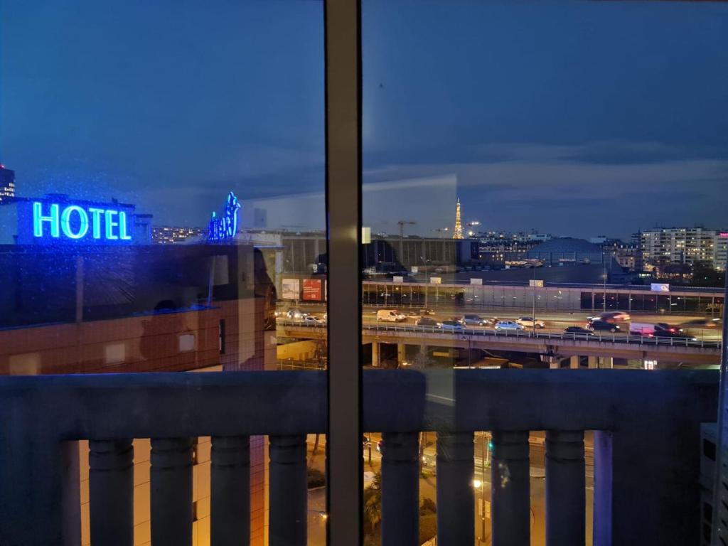 een raam met uitzicht op de stad 's nachts bij APPARTEMENT AVEC VUE SUR LA TOUR EIIFEL in Issy-les-Moulineaux