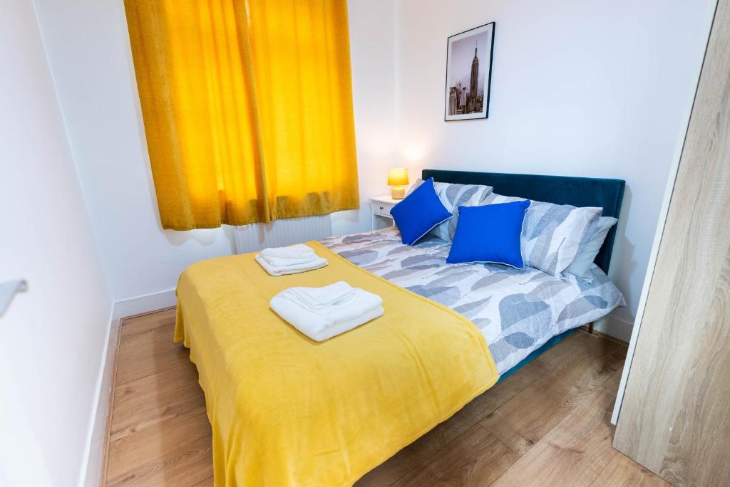 a bedroom with a bed with blue and yellow sheets at Beautiful 4 bedroom house with free parking Luton in Luton