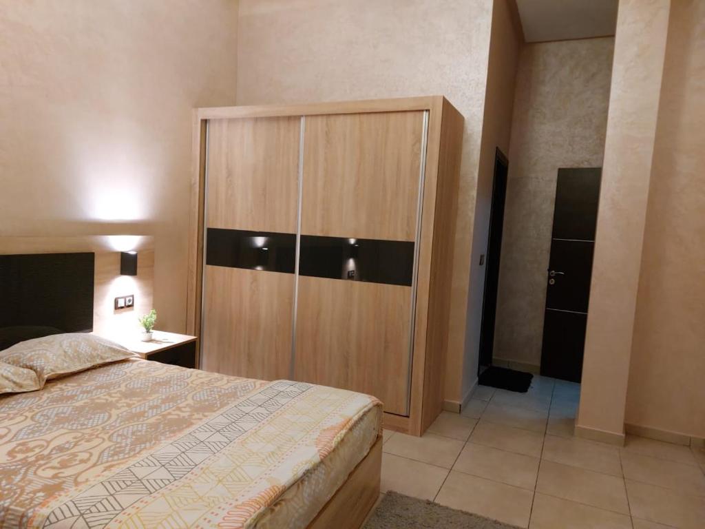 een slaapkamer met een grote houten kast en een bed bij اقامة البحتوري in Nador