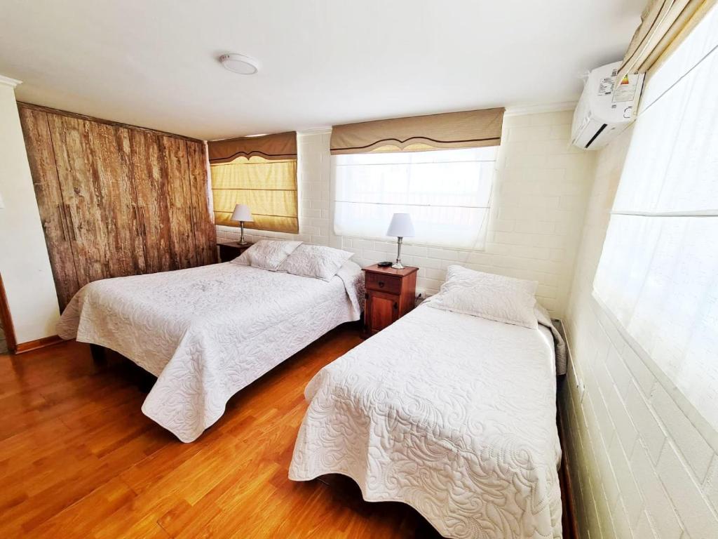 2 Betten in einem Zimmer mit Holzböden in der Unterkunft Hostal Aires del Sur Centro de Rancagua in Rancagua