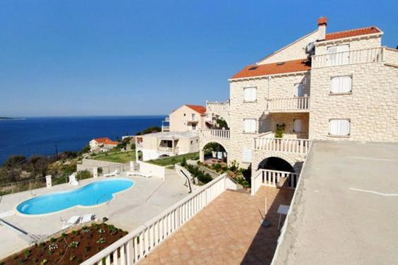 a large building with a swimming pool next to the ocean at Apartments with a swimming pool Soline, Dubrovnik - 4762 in Mlini