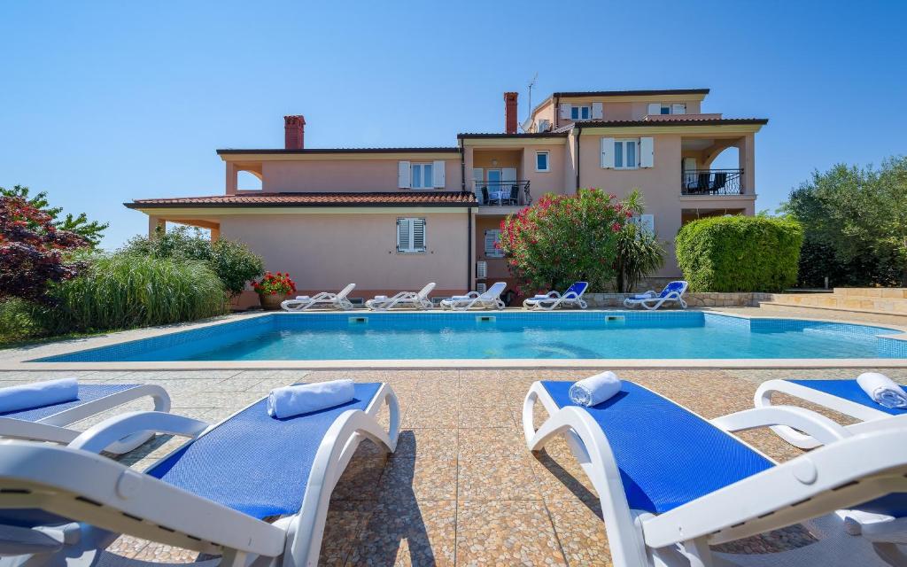 a villa with a swimming pool with chairs and a house at Family friendly apartments with a swimming pool Basanija, Umag - 3402 in Savudrija