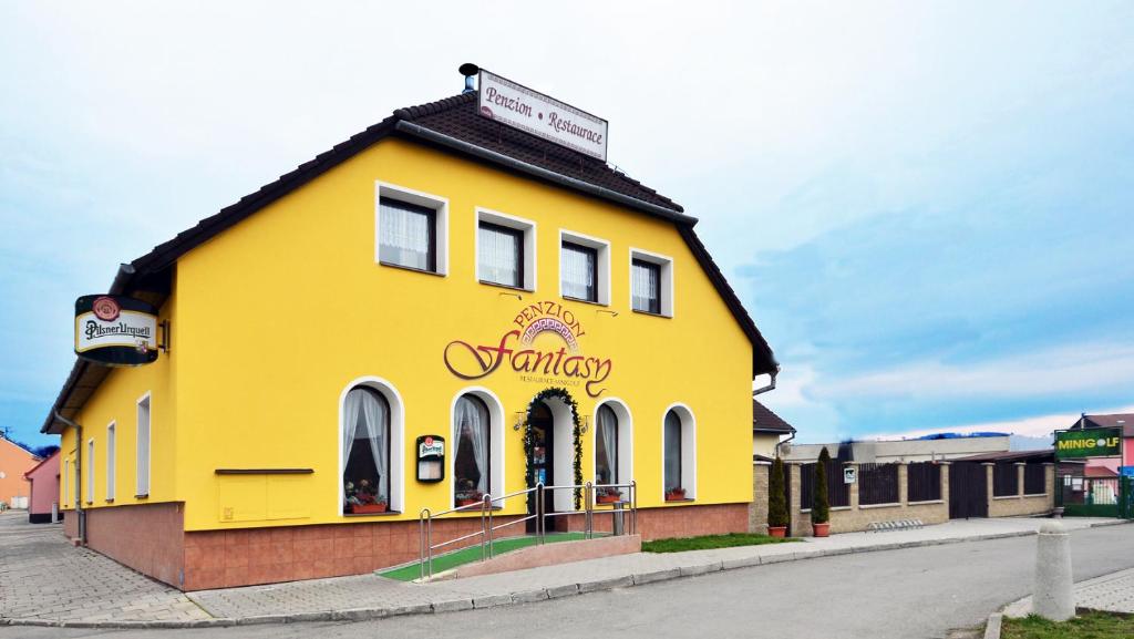 a yellow building on the side of a street at Penzion Fantasy - restaurant in Lipník nad Bečvou