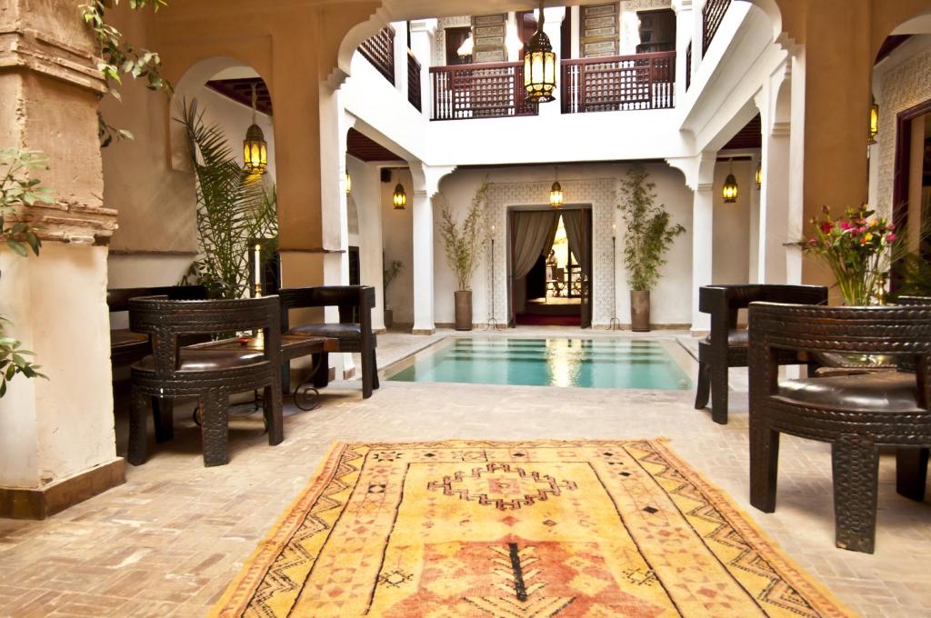 a lobby with a pool and chairs and a table at Riad Aladdin in Marrakesh