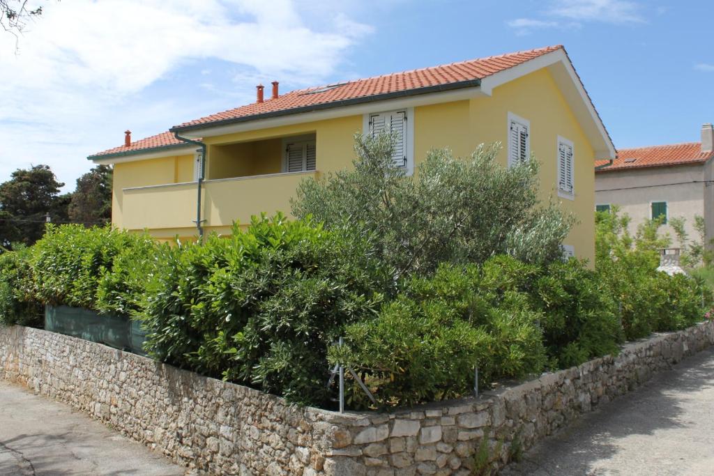 a yellow house with a stone wall at Apartment Nerezine 3451c in Nerezine