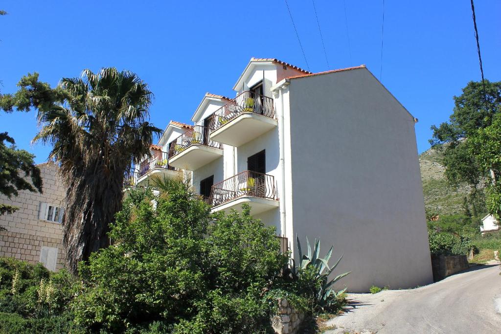 - un bâtiment blanc avec un balcon et un palmier dans l'établissement Apartments and rooms with a swimming pool Cavtat, Dubrovnik - 4733, à Cavtat