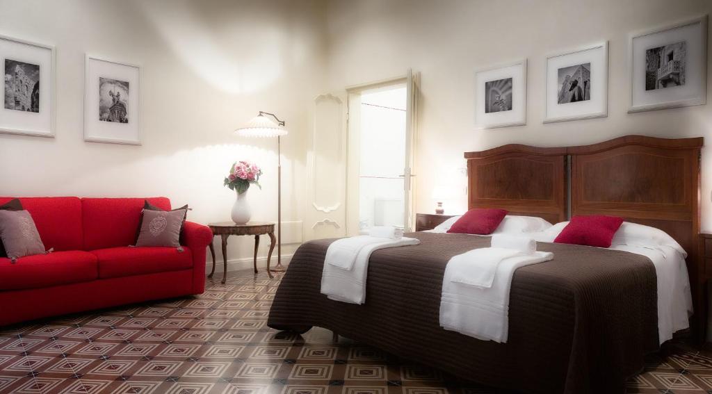 a bedroom with a large bed and a red couch at Palazzo Cerù Bed and Breakfast in Verona