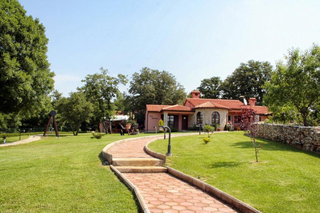 a house in a park with a stone wall at Luxury villa with a swimming pool Belavici, Marcana - 3028 in Barban