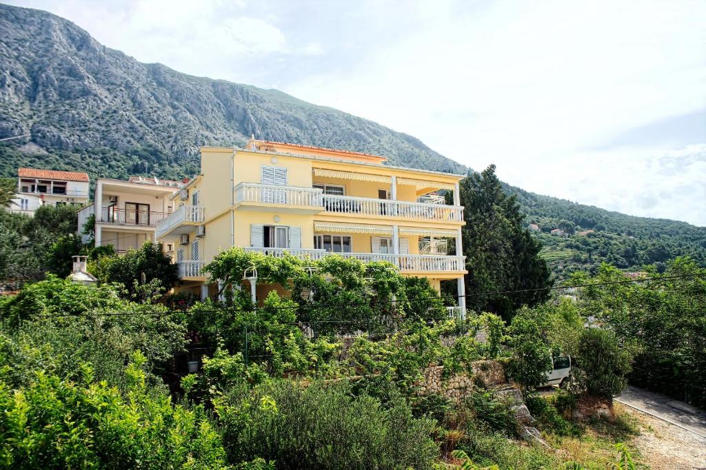 żółty dom na szczycie góry w obiekcie Apartments and rooms by the sea Zivogosce - Porat, Makarska - 2733 w mieście Živogošće